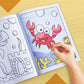The image depicts a hand coloring a book with crayons.