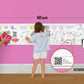 The image depicts a father and his two daughters enjoying a bonding moment while colouring in tamil alphabets roll attached to the wall.
